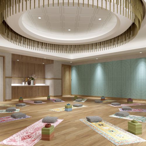 A serene yoga studio with mats, cushions, blocks, and a decorative ceiling light, ready for a class. The room is spacious and well-lit.