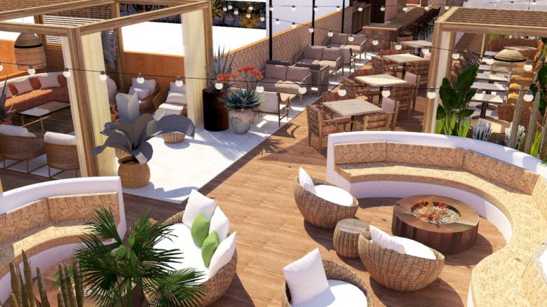 The image shows a stylish outdoor lounge with wooden furniture, cushioned seating, potted plants, and string lights, designed for relaxation and socializing.