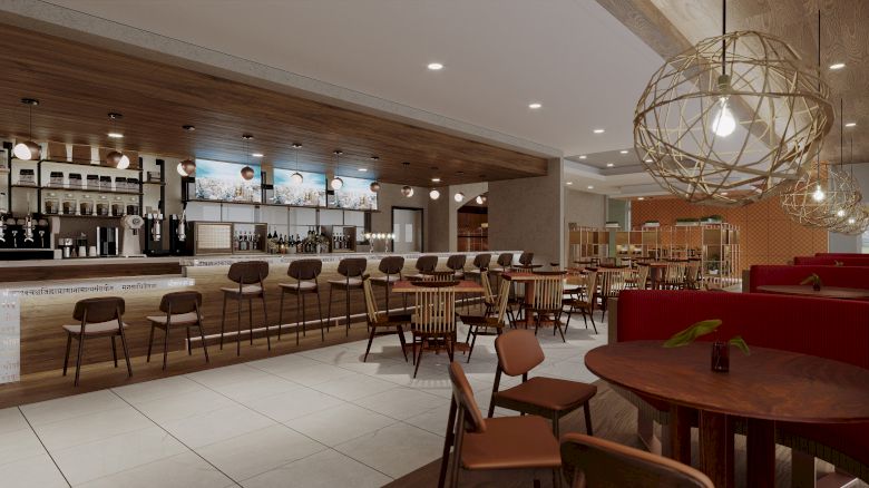 The image shows a modern, well-lit restaurant interior with a long bar counter, wooden chairs, and tables, along with spherical light fixtures.